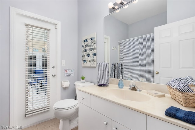 bathroom featuring tile flooring, vanity, and toilet