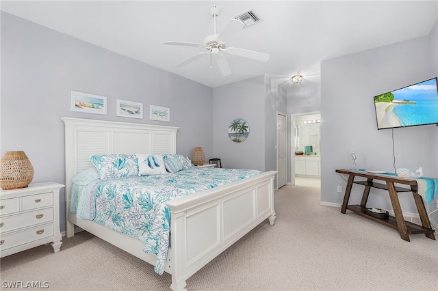 bedroom featuring light carpet, ensuite bathroom, and ceiling fan