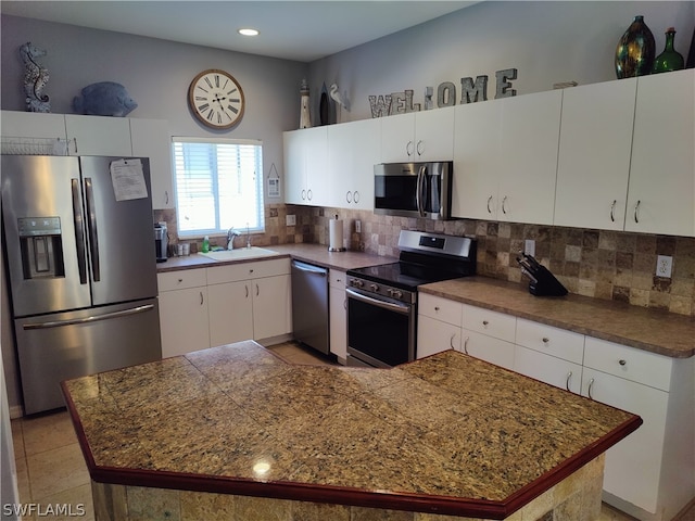 kitchen with white cabinets, backsplash, tile flooring, appliances with stainless steel finishes, and sink