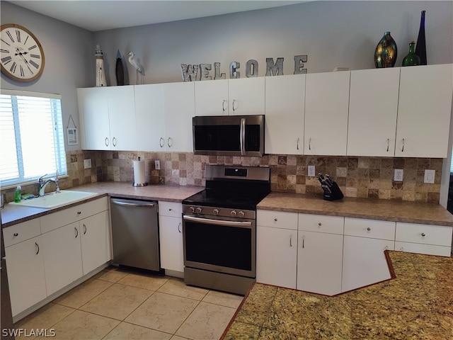 kitchen with appliances with stainless steel finishes, white cabinets, sink, and tasteful backsplash