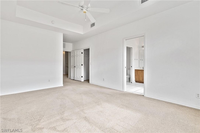 carpeted empty room with ceiling fan and a tray ceiling