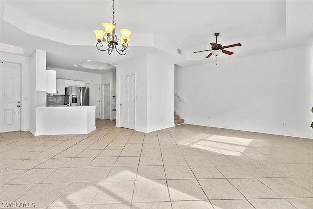 unfurnished living room featuring light tile patterned flooring, a raised ceiling, and ceiling fan with notable chandelier