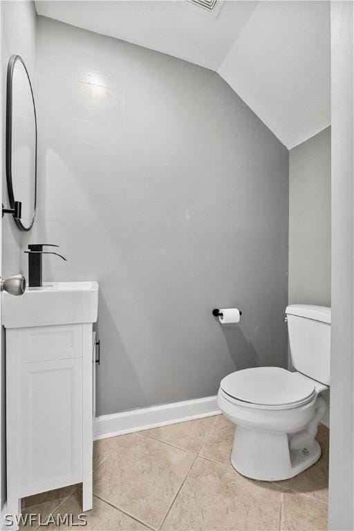 bathroom with tile flooring, vaulted ceiling, toilet, and vanity