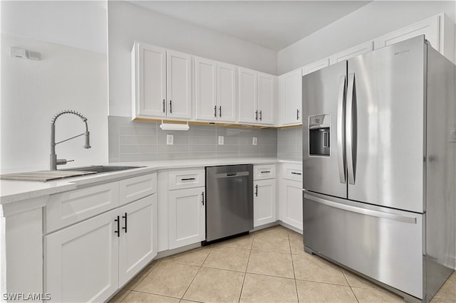 kitchen with light tile flooring, backsplash, white cabinetry, appliances with stainless steel finishes, and sink