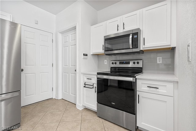 kitchen with light stone countertops, stainless steel appliances, white cabinets, tasteful backsplash, and light tile flooring