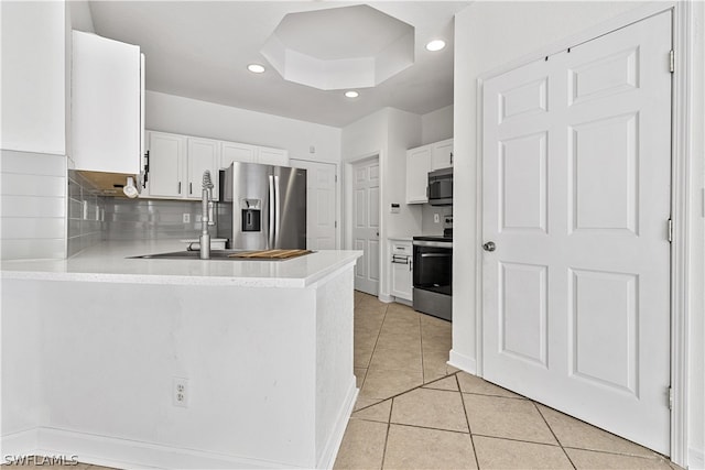 kitchen featuring kitchen peninsula, tasteful backsplash, stainless steel appliances, light tile floors, and white cabinetry