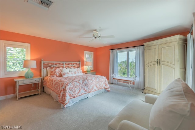 carpeted bedroom featuring multiple windows and ceiling fan