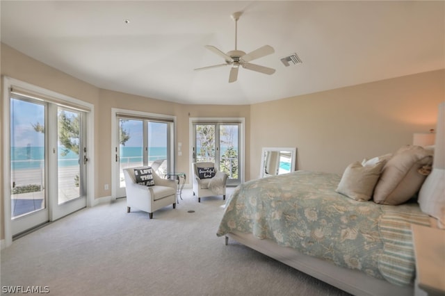 bedroom with multiple windows, ceiling fan, a water view, and access to exterior