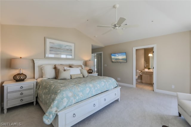 bedroom with ceiling fan, ensuite bathroom, light carpet, and vaulted ceiling