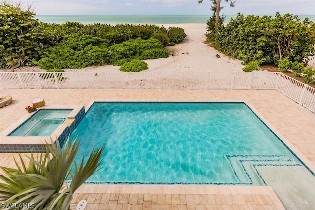 view of swimming pool featuring an in ground hot tub, a water view, and a patio area