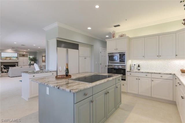 kitchen featuring built in appliances, a center island, light stone counters, and white cabinetry