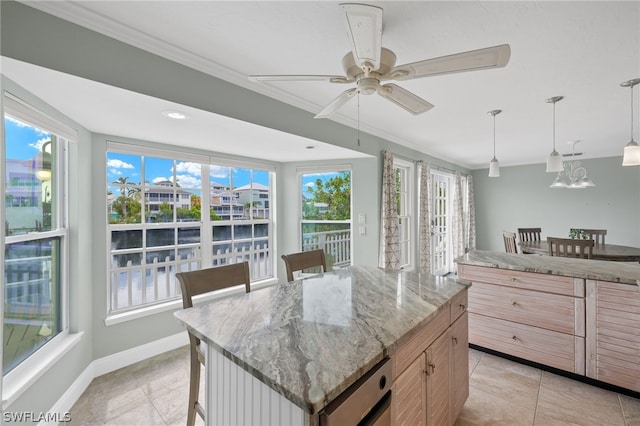 kitchen with light stone countertops, a breakfast bar, ceiling fan with notable chandelier, decorative light fixtures, and a kitchen island