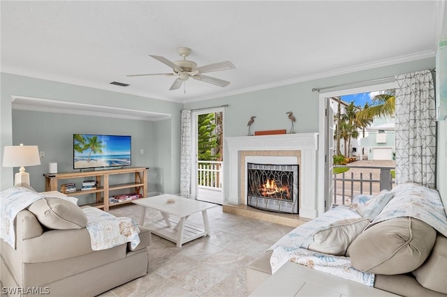 living room featuring a tile fireplace, crown molding, and ceiling fan