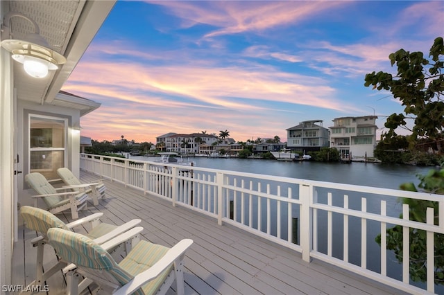 deck at dusk featuring a water view