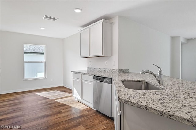 kitchen with light stone countertops, dark hardwood / wood-style flooring, stainless steel dishwasher, sink, and white cabinetry