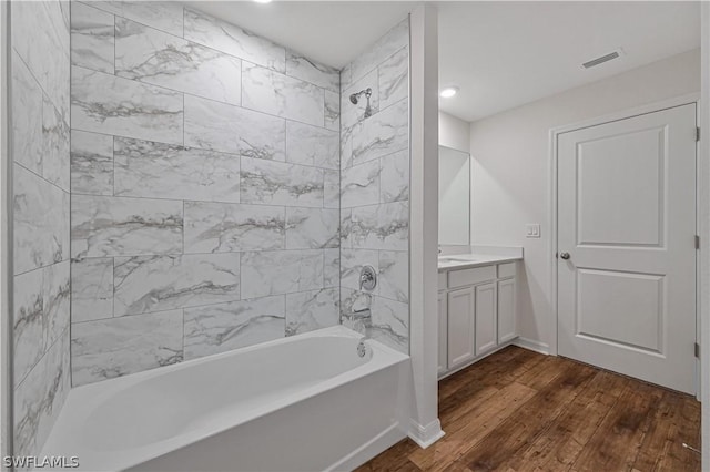 bathroom featuring wood-type flooring, vanity, and tiled shower / bath