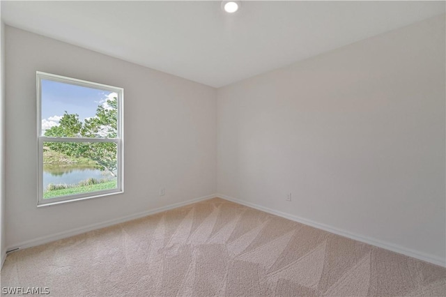 unfurnished room featuring carpet floors and a water view