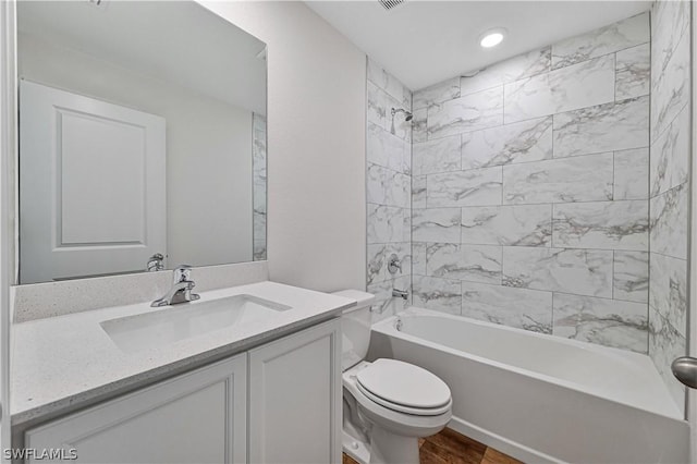 full bathroom featuring hardwood / wood-style flooring, toilet, vanity, and tiled shower / bath