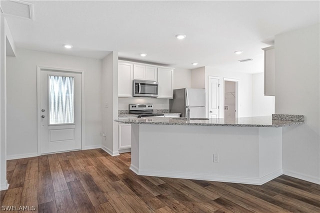 kitchen with light stone countertops, kitchen peninsula, white cabinetry, and stainless steel appliances