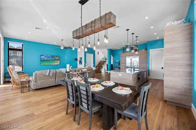 dining room featuring ceiling fan, sink, and light hardwood / wood-style floors