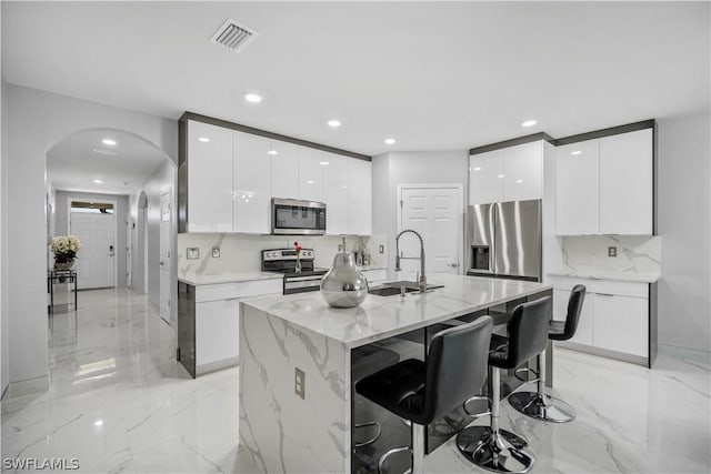 kitchen featuring white cabinetry, stainless steel appliances, sink, and a center island with sink