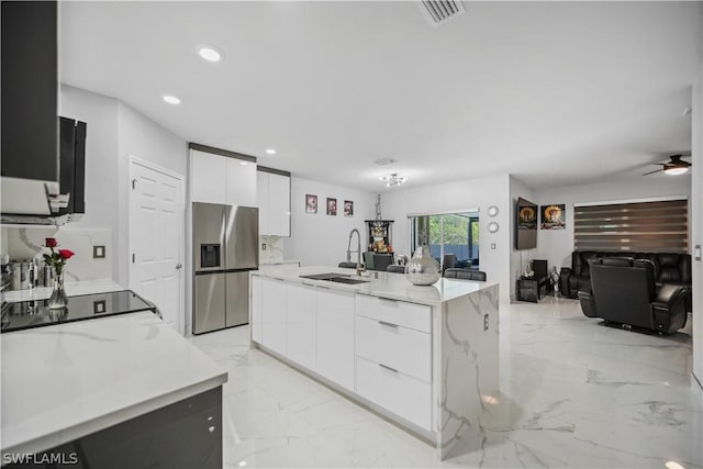 kitchen featuring stainless steel fridge, sink, a center island with sink, and white cabinets