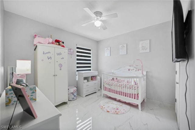 bedroom featuring a nursery area and ceiling fan