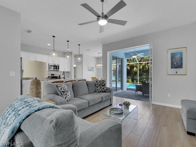 living room with light hardwood / wood-style flooring, ceiling fan, and sink