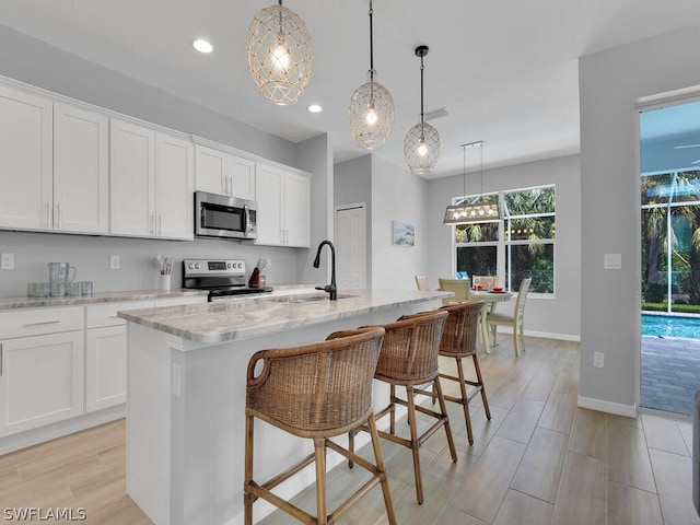 kitchen featuring white cabinetry, a kitchen island with sink, sink, and appliances with stainless steel finishes