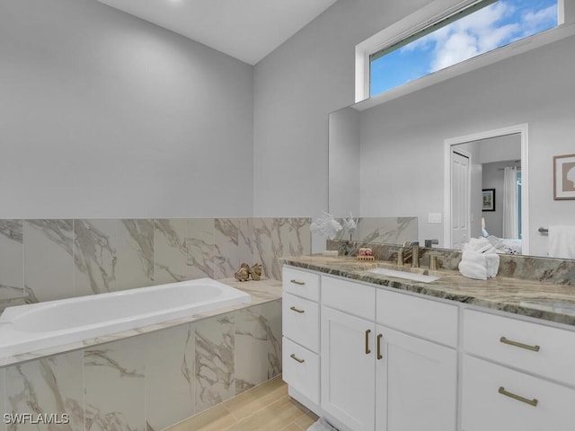 bathroom featuring tiled bath and vanity