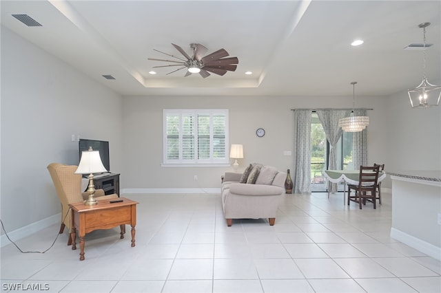 tiled living room featuring a tray ceiling, plenty of natural light, and ceiling fan