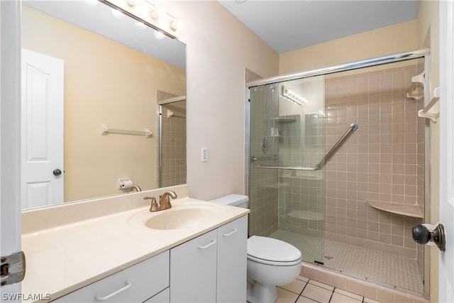 bathroom featuring tile patterned floors, vanity, a shower with shower door, and toilet