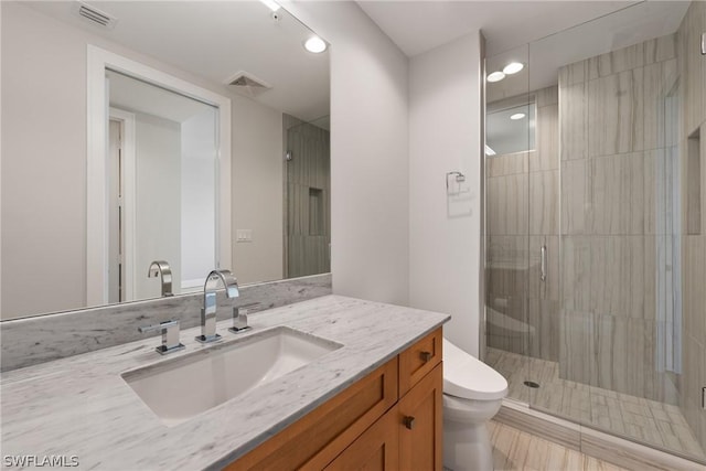 bathroom with vanity, toilet, and a shower with door