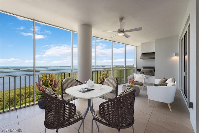 sunroom with ceiling fan and a water view