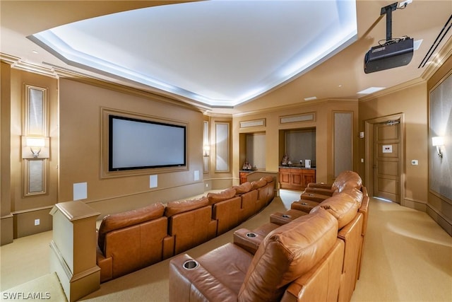 home theater room featuring a tray ceiling, light colored carpet, and ornamental molding