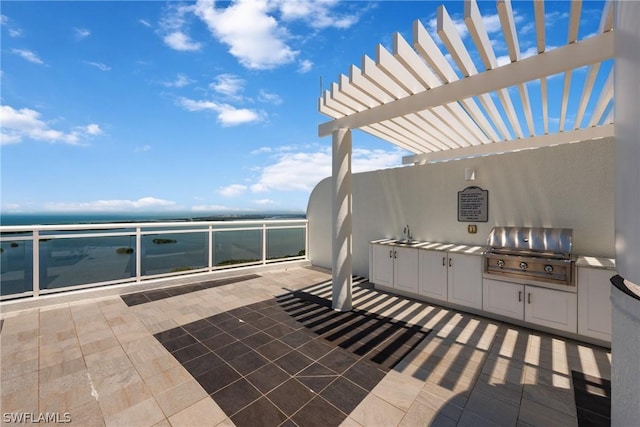 view of patio featuring a pergola, area for grilling, a water view, and an outdoor kitchen