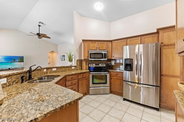 kitchen featuring ceiling fan, stainless steel appliances, stone counters, light tile flooring, and sink