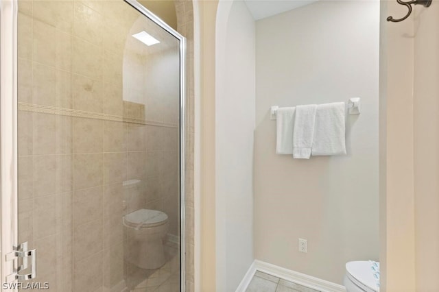 bathroom featuring tile flooring, a shower with shower door, and toilet