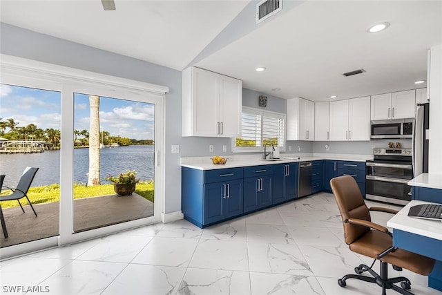 kitchen featuring a water view, blue cabinets, sink, appliances with stainless steel finishes, and white cabinetry