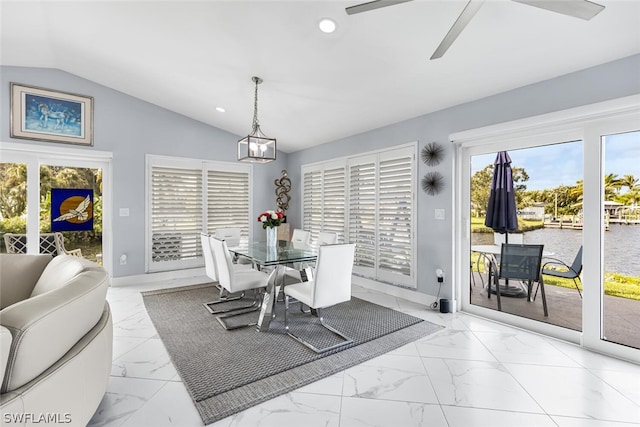 dining space with ceiling fan, a water view, and vaulted ceiling