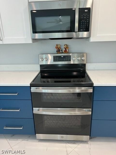 kitchen with blue cabinets, white cabinets, and appliances with stainless steel finishes