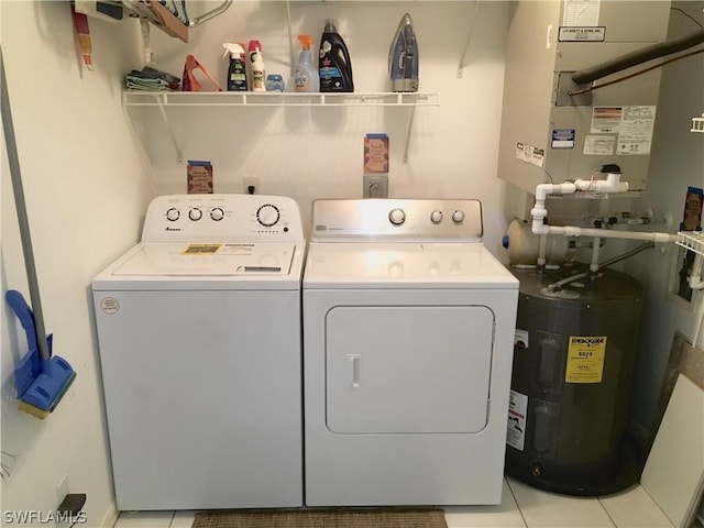 clothes washing area with washer and clothes dryer, light tile patterned floors, and water heater