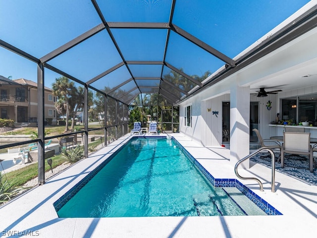 view of swimming pool featuring ceiling fan, a patio area, and glass enclosure