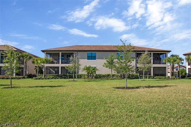 back of property with a yard and stucco siding