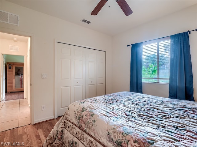 bedroom with light hardwood / wood-style floors, ceiling fan, and a closet