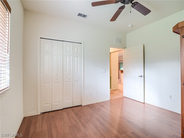 unfurnished bedroom with ceiling fan, wood-type flooring, and a closet