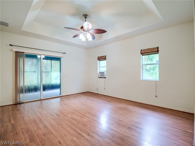 unfurnished room with plenty of natural light, a raised ceiling, and light hardwood / wood-style flooring