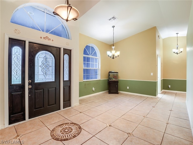 foyer featuring a chandelier, vaulted ceiling, and light tile patterned floors