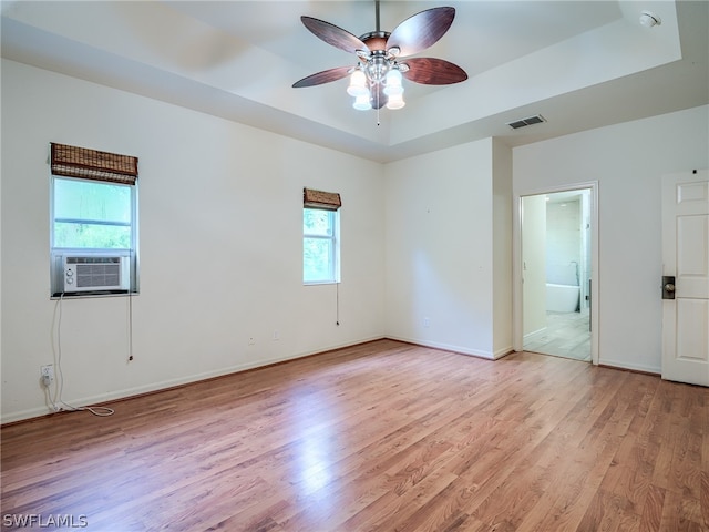 spare room featuring light wood-type flooring, a wealth of natural light, cooling unit, and a raised ceiling