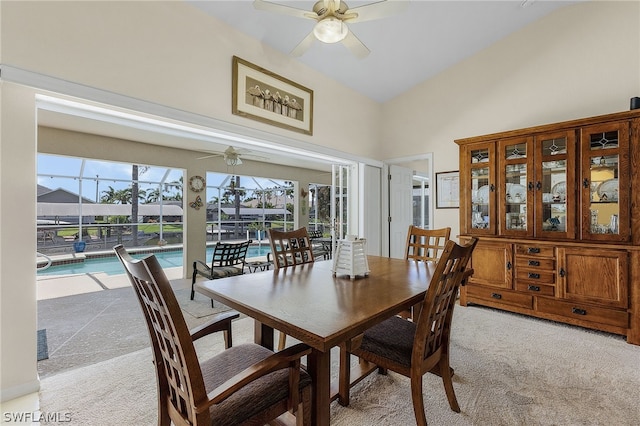 carpeted dining area with ceiling fan and high vaulted ceiling